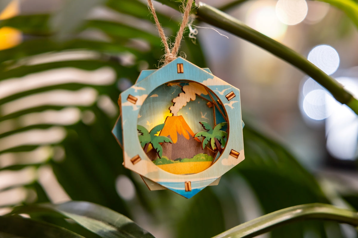 Decorative 3D ornament with a tropical volcano scene hanging on a branch