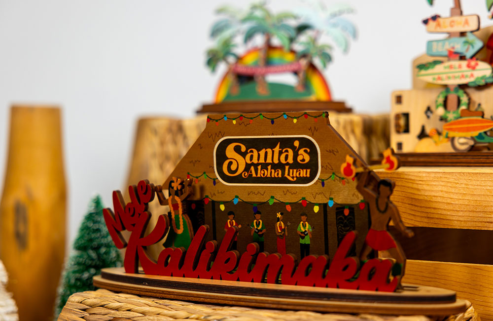Wooden decorative sign with 'Santa's Aloha Luau' and 'Kalikimaka' text, surrounded by festive decorations.