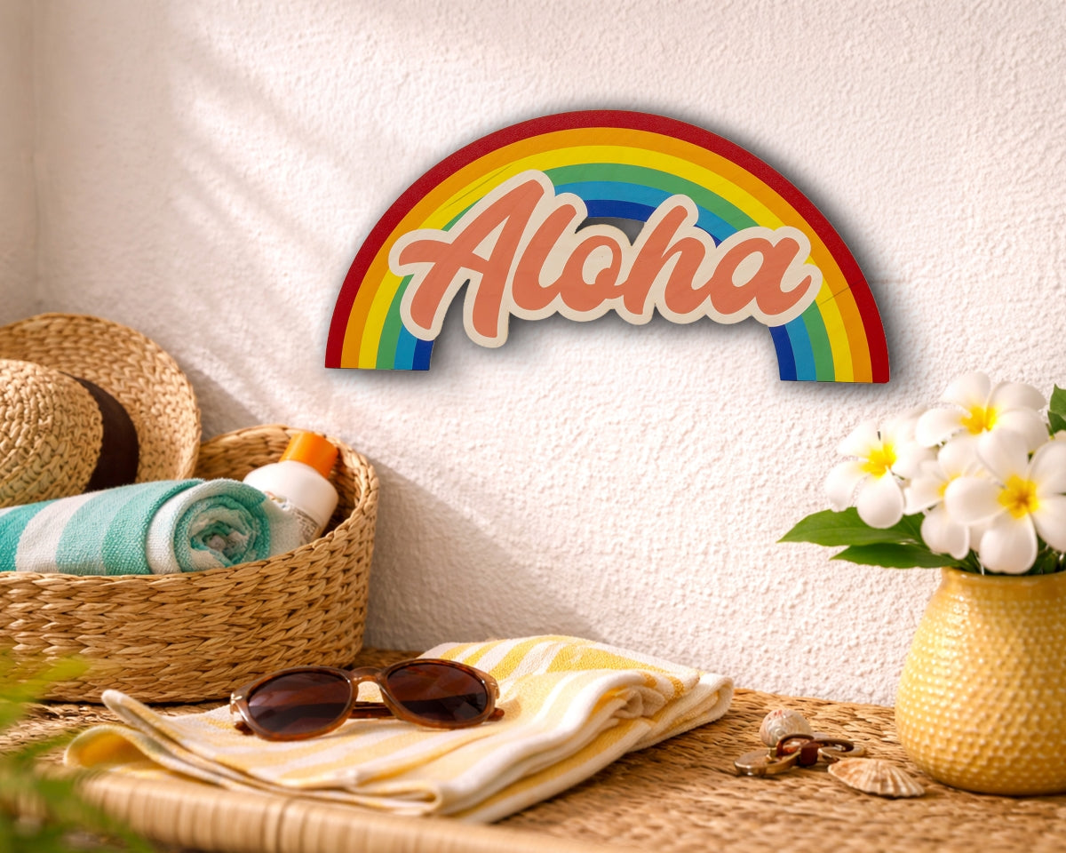 Decorative rainbow sign with 'Aloha' on a wall above a table with beach items.