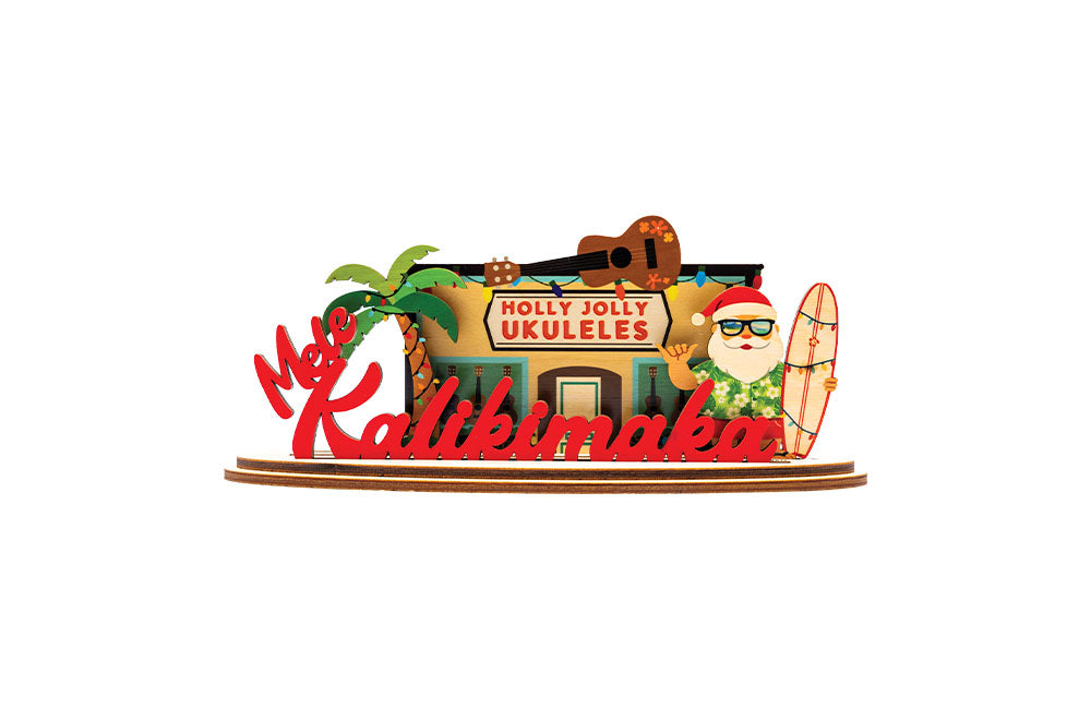 Decorative 3D holiday sign with 'Holly Jolly Ukuleles' shop and a Shaka Santa Claus figure holding a surfboard next to a palm tree on a white background.