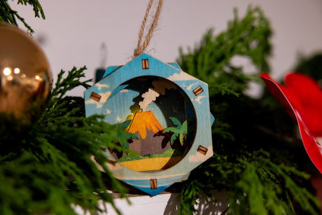 Decorative 3D ornament with a tropical scene hanging on a Christmas tree.