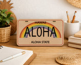 Wooden sign with rainbow and 'Hawaii Aloha Aloha State' text on a desk with stationery items.