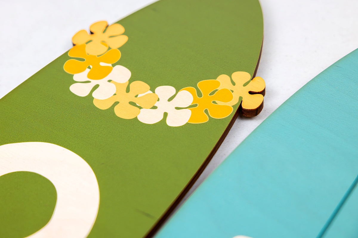 Close up of decorative surfboard with flowers on a green background
