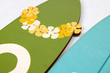 Close up of decorative surfboard with flowers on a green background